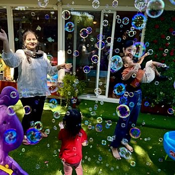 Caregivers and children playing in a cloud of bubbles