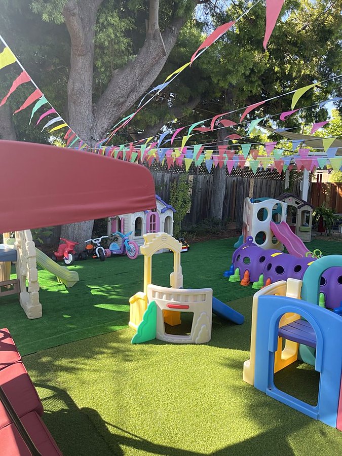 Sunny fenced play yard with slides, playhouses, and climbing toys