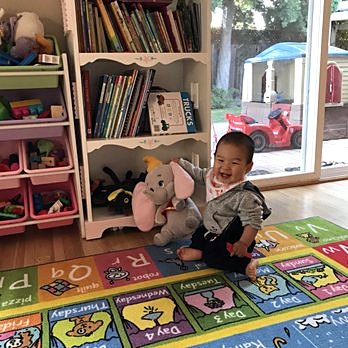 Happy baby by the book corner with a plush elephant