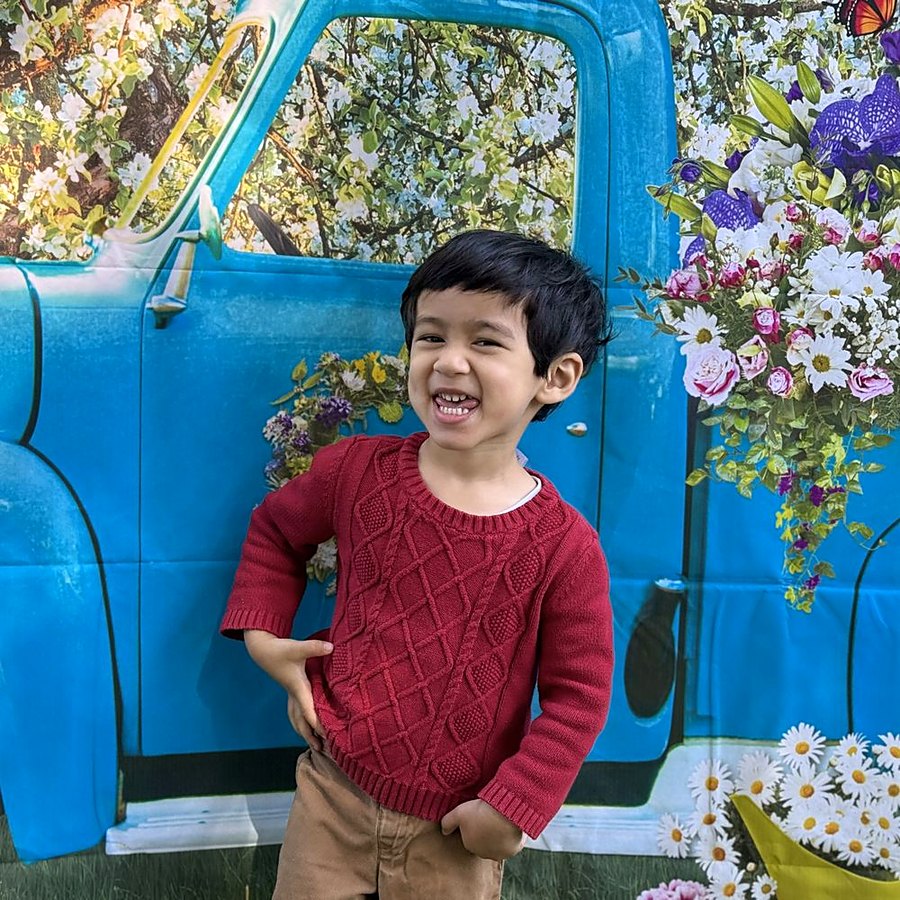 Boy smiling at spring picture day with flower truck backdrop
